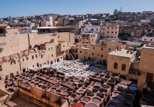 The high-angle view of the cityscape and traditional tannery vats on a sunny day in Fes